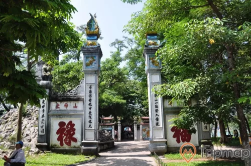 Cánh cổng khắc chữ trên tường và cây cối xanh tươi