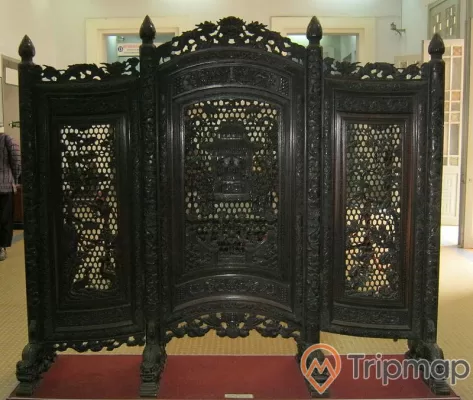 tấm binh phong gỗ điêu khắc màu đen đặt trên tấm thảm đỏ ở trong nhà