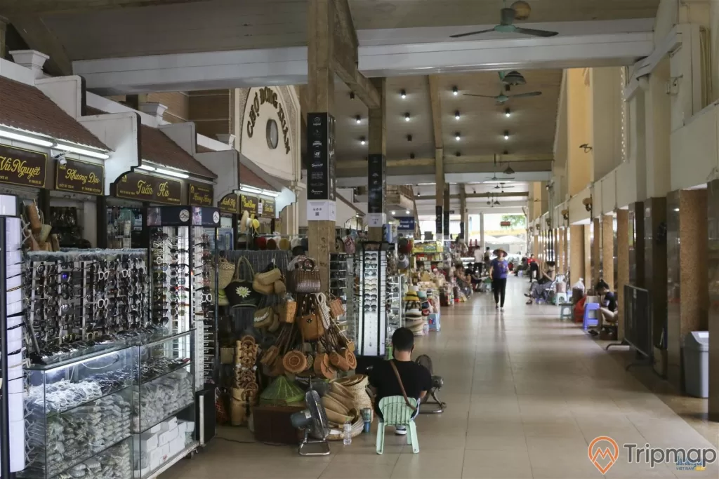 cửa hàng bán kính thời trang và cửa hàng bán túi xách trong chợ đồng xuân, 1 người đang ngồi và 1 người đang đi bộ, 2 chiếc quạt phía trên trần