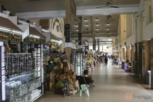 cửa hàng bán kính thời trang và cửa hàng bán túi xách trong chợ đồng xuân, 1 người đang ngồi và 1 người đang đi bộ, 2 chiếc quạt phía trên trần