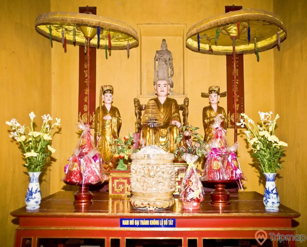 bàn thờ tượng Lý Quốc Sư và 2 thị giả, 2 bình hoa loa kèn, 2 đĩa bánh kẹo đồ cúng, 1 bát lư hương tất cả ở trên bàn
