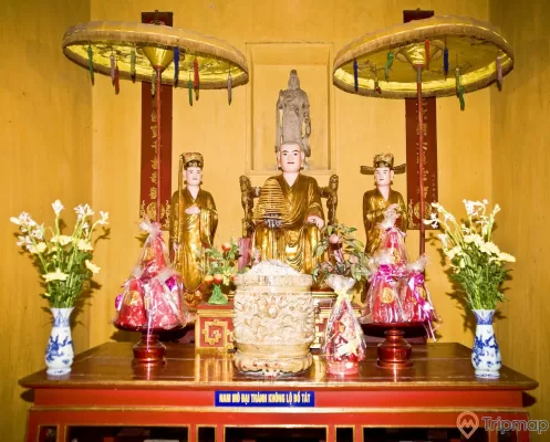 bàn thờ tượng Lý Quốc Sư và 2 thị giả, 2 bình hoa loa kèn, 2 đĩa bánh kẹo đồ cúng, 1 bát lư hương tất cả ở trên bàn