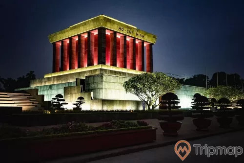 Lăng chủ tịch Hồ Chí Minh đèn điện màu đỏ và màu trắng, bầu trời tối và chậu cây cảnh cây cối ở cạnh Lăng Bác